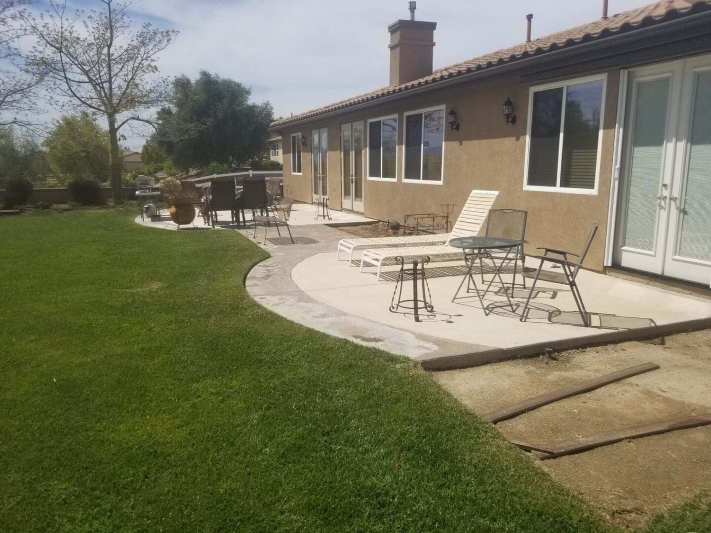 A patio with chairs and tables in the back yard.