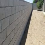 A concrete block wall with a sidewalk in the background.