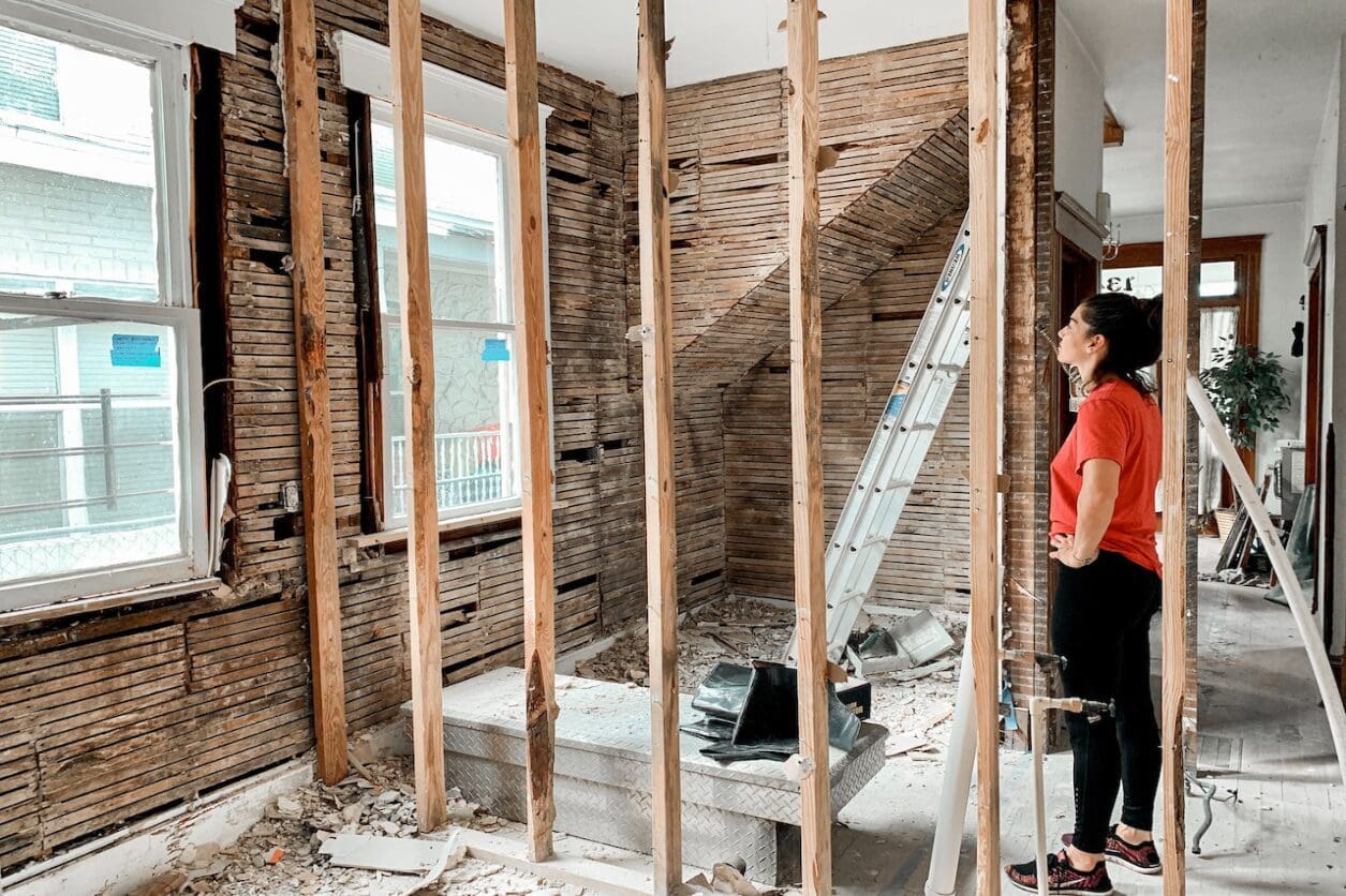 A woman standing in the middle of a room with some wood.