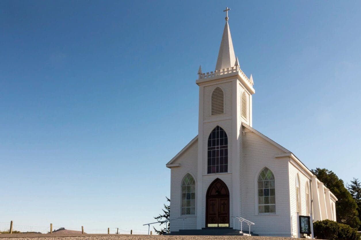 A white church with a steeple and cross on top.