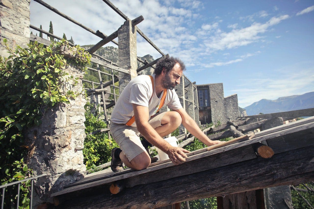 A man is climbing on the roof of an old building.