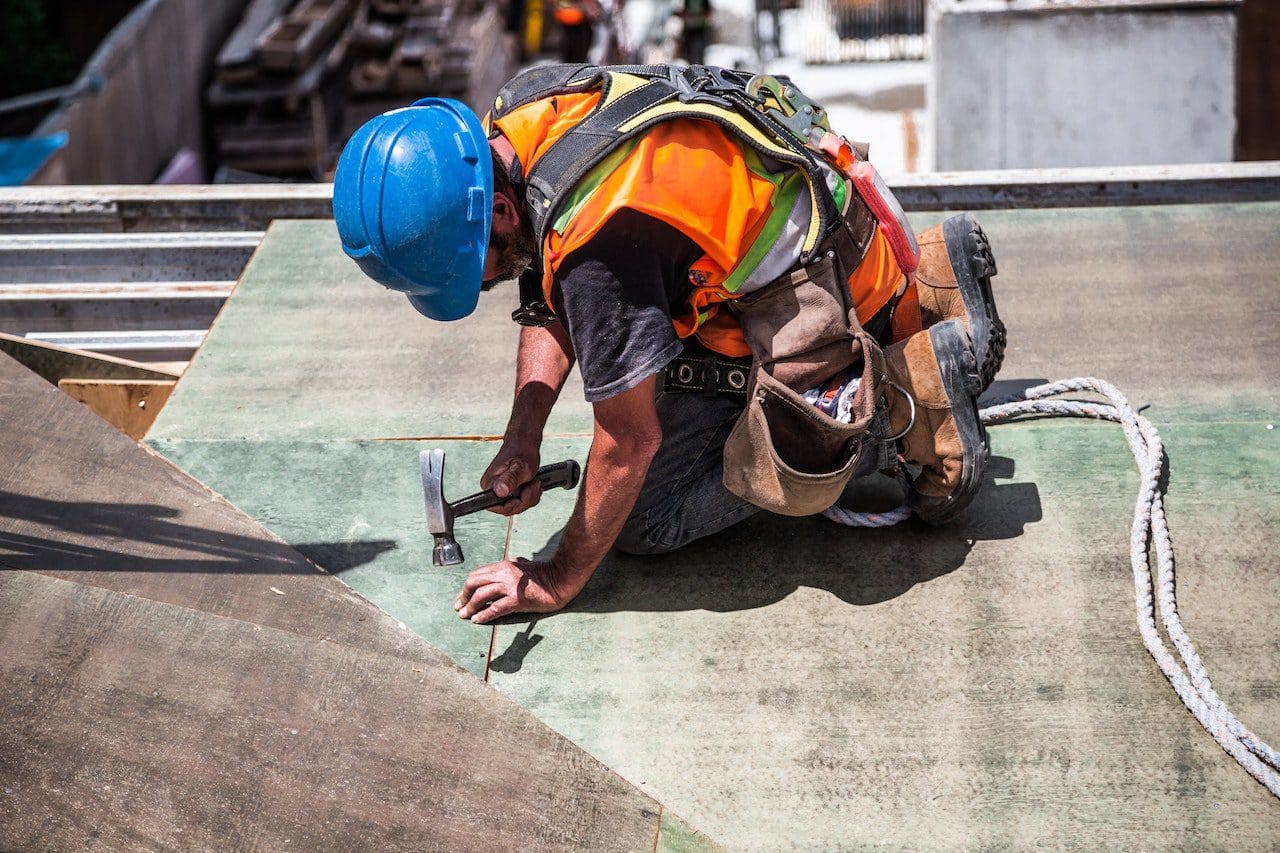 A construction worker is on the ground with his hands in his pockets.