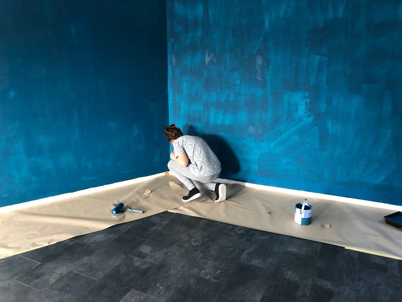 A person sitting on the ground with paint cans