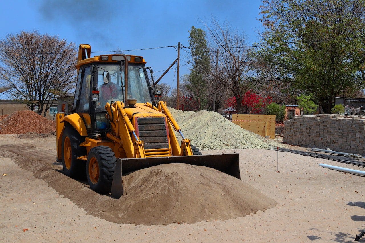 A yellow tractor is parked in the sand.