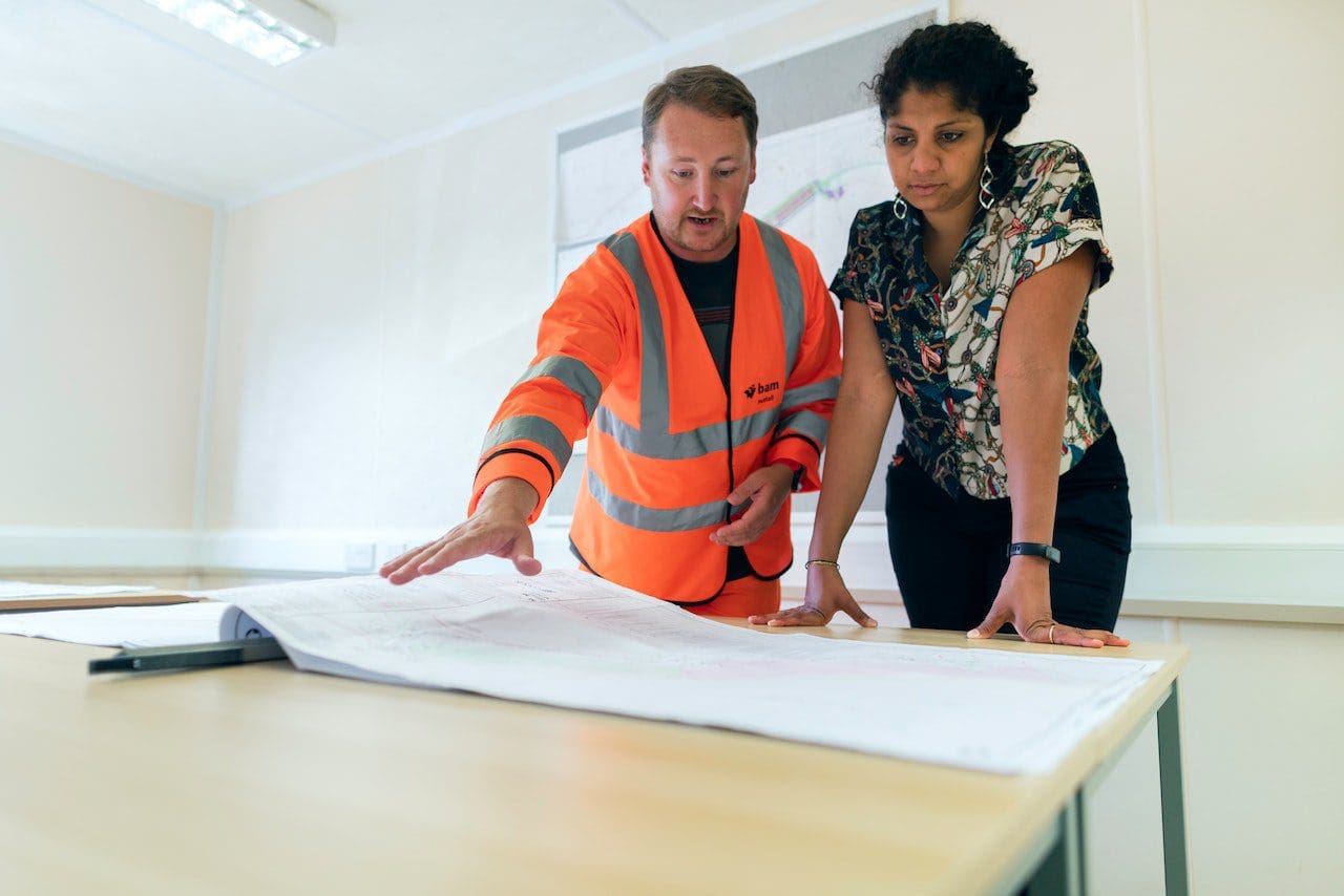 A man and woman looking at plans on top of a table.